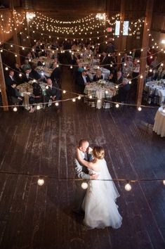 a bride and groom share their first dance at their wedding reception in an old barn