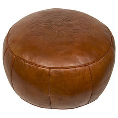 a large brown leather ottoman sitting on top of a white floor