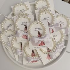 several tags with pearls and bows are on a white tray next to some other items