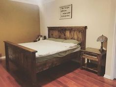 a wooden bed frame in a bedroom with hard wood flooring and light colored walls