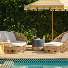 two wicker lounge chairs next to a pool with an umbrella over it and a yellow bag on the side