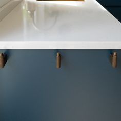 a white counter top with brass handles in a kitchen