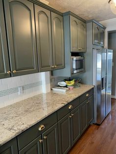 a kitchen with green cabinets and marble counter tops