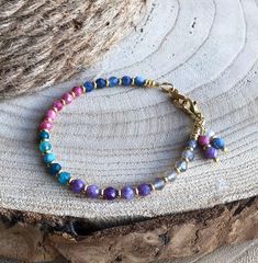 This pretty gemstone bracelet just shouts spring with its soft and refreshing colors. Great on its own on your arm or stacked with other bracelets that you love. Versatile too - wear it casual during the day and dressed up for that special occasion. 5 groups of 5 gemstones are highlighted and separated by gold Czech glass spacers while 2 charms (thulite & lepidolite and freshwater pearl & kyanite) which I handcrafted decorate the closure. Securing the piece are a gold filled lobster clasp and decorative gold plated infinity loop. Gemstones are faceted approximately 4mm rounds and include: Labradorite (gray with flashes of blue) Lepidolite (shades of purple) Apatite (shades of teal) Thulite (shades of pink) Kyanite (medium blue with flashes of light) Photo gallery #3 shows this colorful gem Adjustable Multicolor Crystal Gemstone Bracelet, Adjustable Multicolor Gemstone Crystal Bracelet, Adjustable Rainbow Crystal Bohemian Bracelet, Blue Natural Stones Bracelets For Friendship, Blue Natural Stone Bracelets For Friendship, Blue Natural Stones Friendship Bracelets, Blue Gemstone Beads Bracelets For Friendship, Bohemian Rainbow Beaded Bracelets With Natural Stones, Dainty Blue Bracelets With Natural Stones