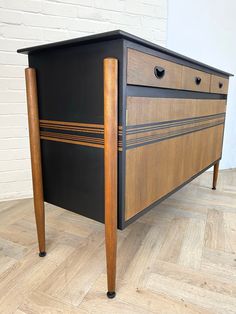 a black and brown dresser sitting on top of a hard wood floor