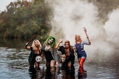 group of women in costumes standing in water with steam rising from the ground behind them