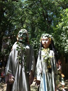 two people dressed in costumes standing next to each other on a field with trees behind them