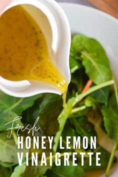 a white bowl filled with greens and dressing being drizzled on top of it