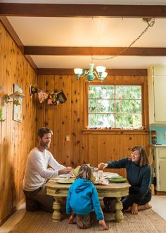 a man and two children sitting at a table in a room with wood paneling