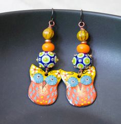 Whimsical owl earrings featuring delightful orange, yellow and blue enamel charms. I love their big mesmerizing eyes. They are topped with spotted blue, green and yellow lampwork beads, bright orange glass spacers, copper beads and yellow Czech glass beads. These earrings measure 2 3/4 inches in total length and hang on niobium earring hooks. Return to shop: bstrung.etsy.com More links where you can find me: Facebook: http://www.facebook.com/bstrung Pinterest: http://pinterest.com/bstrung Instag Whimsical Yellow Jewelry With Ear Wire, Artsy Orange Jewelry With Matching Earrings, Orange Enamel Earrings Nickel Free, Handmade Whimsical Yellow Earrings, Whimsical Yellow Dangle Earrings, Yellow Whimsical Dangle Earrings, Whimsical Handmade Orange Earrings, Playful Orange Dangle Jewelry, Bohemian Orange Earrings