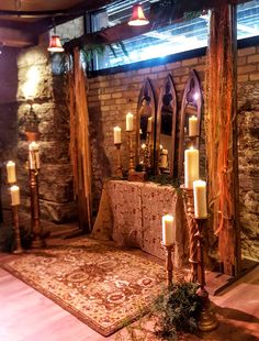 candles are lit in the middle of a room decorated with stone walls and rugs