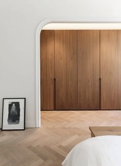 an empty bedroom with wooden closets and pictures on the wall in front of it