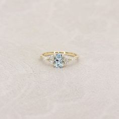 a gold ring with an aqua blue topazte and two white diamonds on it