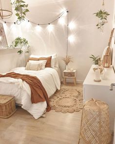 a bedroom with white walls and wooden flooring, lights strung from the ceiling over the bed