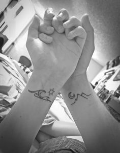 two people with tattoos on their arms holding hands up to each other in the air