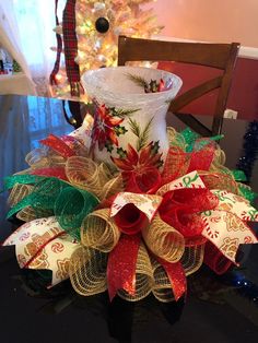 a decorated vase sitting on top of a table next to a christmas tree with lights in the background