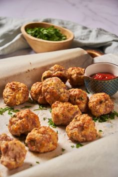 some meatballs are on a tray with ketchup and parsley next to it