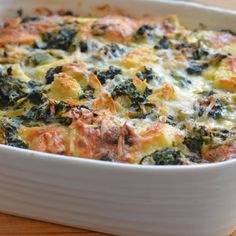 a casserole dish with spinach and cheese in it on a wooden table