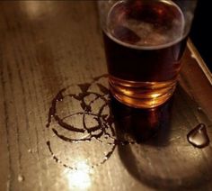 a shot glass sitting on top of a wooden table next to an object that looks like a circle