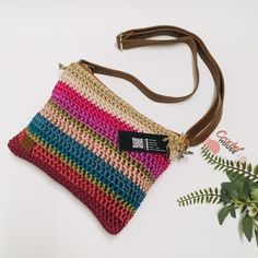 a multicolored purse sitting on top of a white table next to a plant