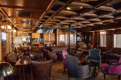 the interior of an old fashioned bar with leather chairs and wooden paneling on the walls