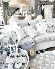 a living room filled with white furniture and lots of pillows on top of it's couch