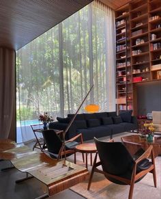 a living room filled with furniture next to a window covered in lots of bookshelves