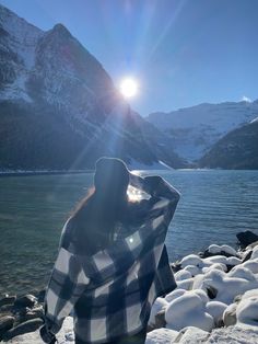 a woman standing on top of a snow covered ground next to a body of water