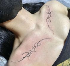 a woman laying on top of a bed with her back turned to the camera and tattoos on her chest