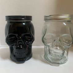 two glass jars with black and clear skull lids