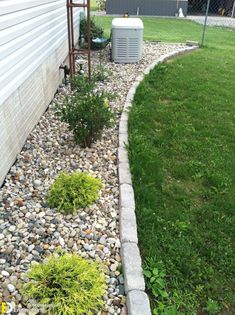 a small garden with rocks and grass next to a house