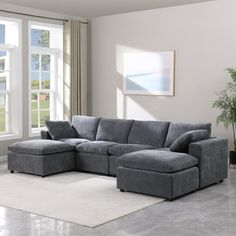 a living room with a large gray sectional couch and white rugs on the floor