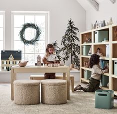 two children sitting at a table in front of bookshelves with christmas decorations on them