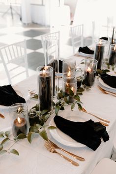 the table is set with candles and black napkins