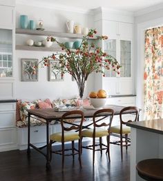 a dining room table with chairs and a vase filled with flowers on top of it