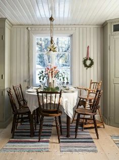 a dining room table and chairs in front of a window with wreaths on it