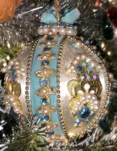 an ornament hanging from a christmas tree with pearls and other ornaments on it