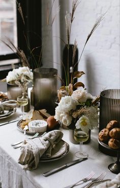 the table is set with silverware and flowers in vases on top of it