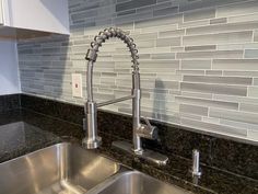 a stainless steel sink and faucet in a kitchen with black granite counter tops