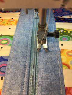 the sewing machine is working on the blue jean pants that have been sewn together