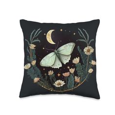 a black pillow with a white butterfly on it and flowers in the foreground, against a dark background