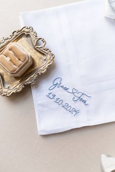 a white napkin with blue writing on it sitting next to a silver tray and tie