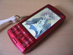 a red cell phone sitting on top of a table next to a pair of scissors