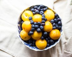 a bowl filled with blueberries and lemons on top of a white table cloth