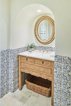 a bathroom with blue and white tiles on the walls, sink and mirror above it