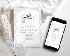 a phone next to a baby shower card on a white table with blue gingham