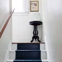 the stairs are painted white and have blue steps leading up to an open window with a framed picture on it