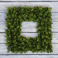 the letter e made out of green leaves on top of a wooden table with white boards