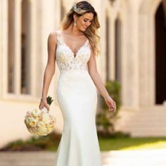 a woman in a white wedding dress walking down the street with flowers on her bouquet