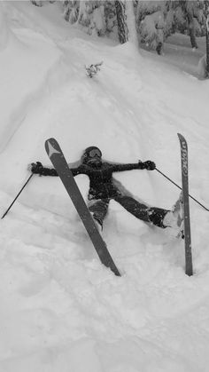 a person on skis laying in the snow with their arms out and legs crossed